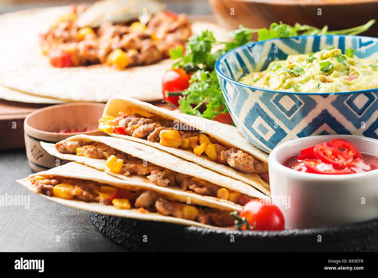 Hausgemachtes Rindfleisch mexikanische Fajitas mit Tortilla und Guacamole und Salsa Saucen auf schwarzem Hintergrund Stockfoto