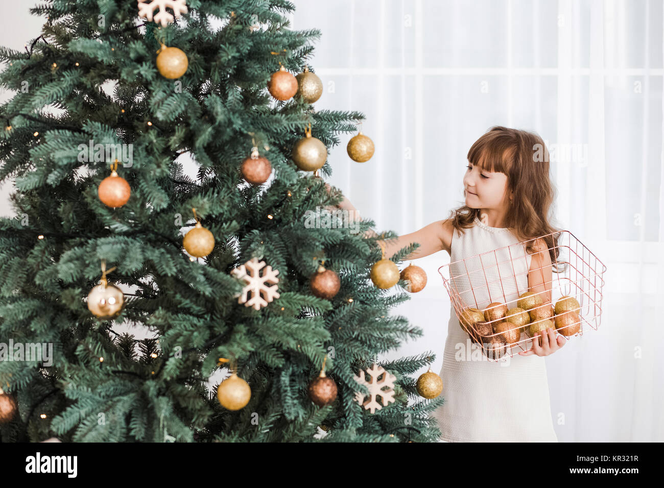 Schöne Mädchen zieren riesige grüne Weihnachtsbaum für Urlaub Feier. Horizontale Farbfotografie. Stockfoto
