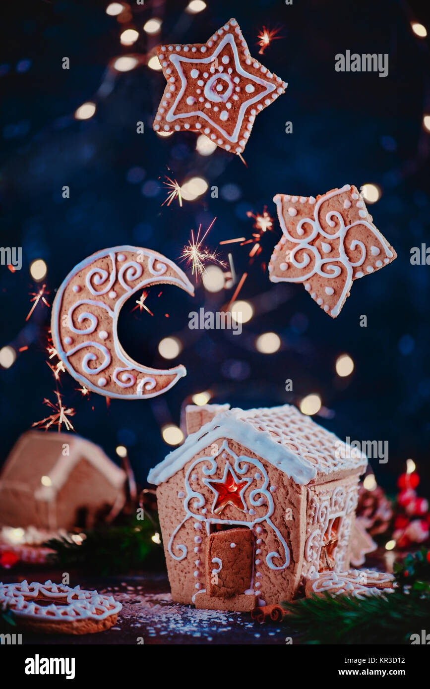 Weihnachten backen Konzept mit Lebkuchenhaus, glänzenden Karamell Windows, Keks Sterne und Mondsichel. Festliche essen Fotografie mit Lichterketten Stockfoto