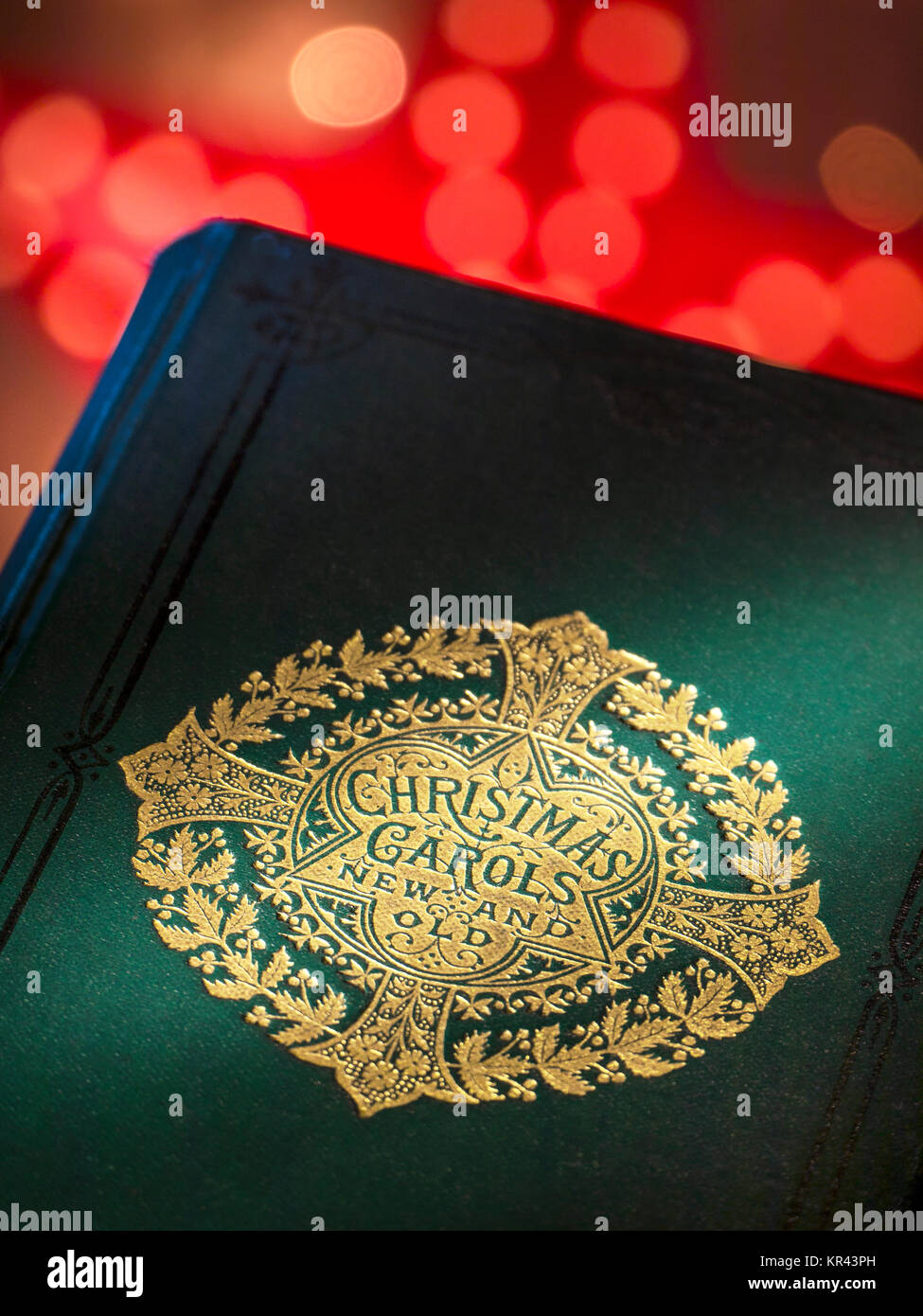 „Christmas Carols“ – Alte und Neue Musik-Buchcover mit warmen, einladenden Weihnachtslichtern hinter dem traditionellen musikalischen Weihnachtsfest. Stockfoto