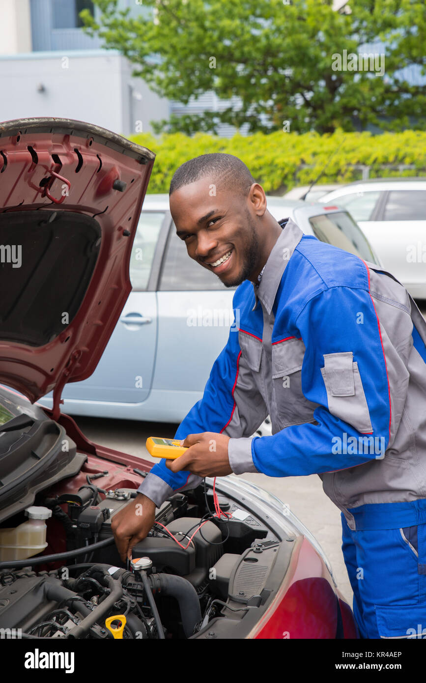 Mechaniker mit Multimeter prüfen Auto Batterie Stockfoto