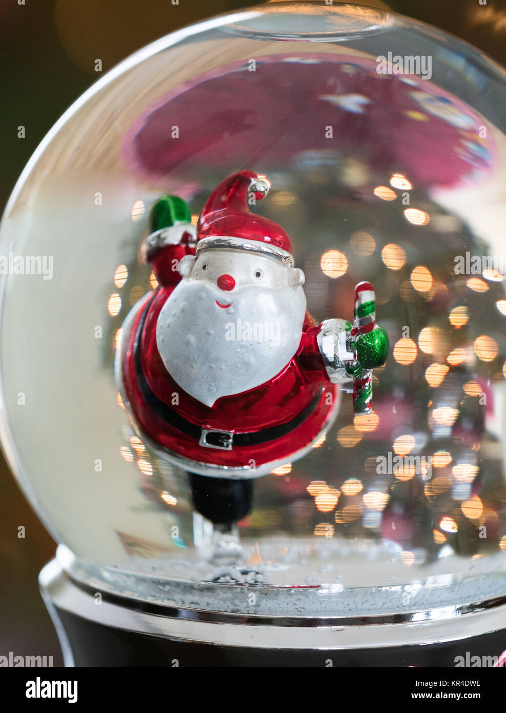 Nahaufnahme eines skating Santa in einer Schneekugel mit goldenen Punkten von Licht im Hintergrund. Stockfoto