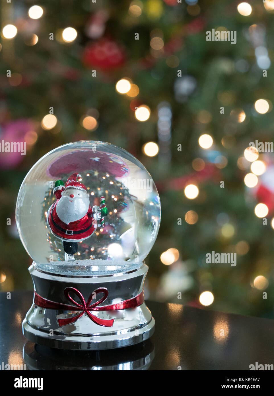 Nahaufnahme eines skating Santa in einer Schneekugel mit dem goldenen Punkte der Weihnachtsbaum leuchtet im Hintergrund. Geringe Tiefenschärfe. Bild kopieren Stockfoto