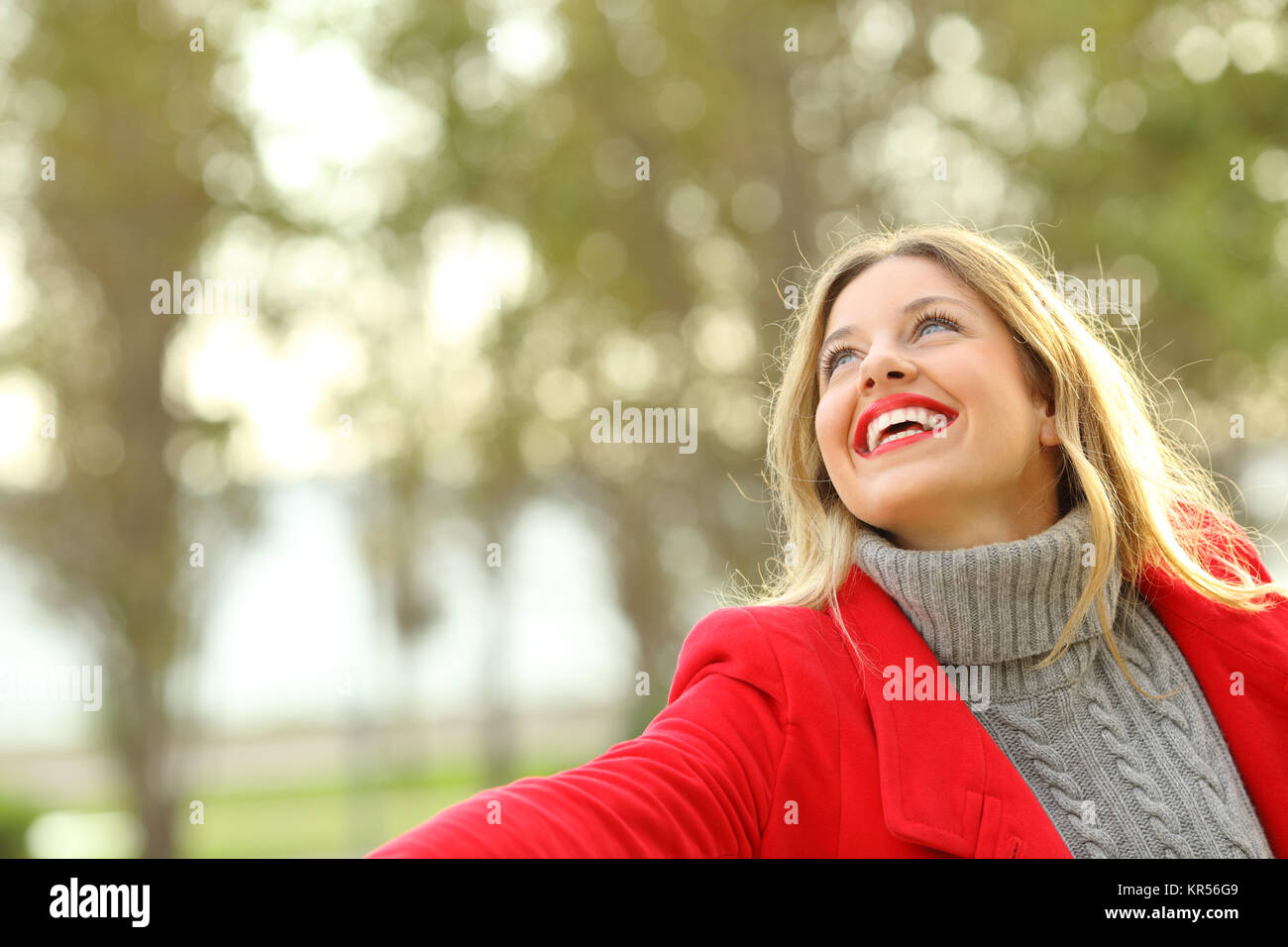 Lustige Frau trägt eine rote Jacke in einem Park Spaß im Winter Stockfoto