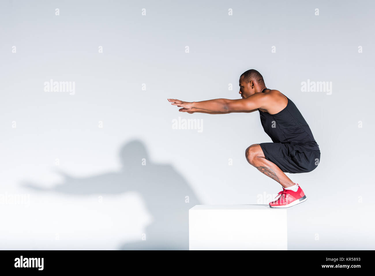 Seitenansicht der jungen afrikanischen amerikanischen Sportler bereit auf grau zu springen Stockfoto