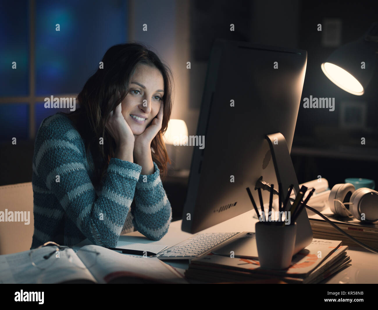 Glücklich lächelnde Frau Entspannung zu Hause und Verbinden mit Ihrem Computer, Sie ist das Anschauen von Videos online Stockfoto