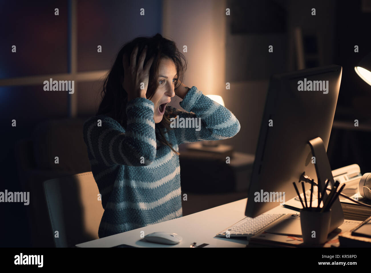 Schockiert Frau mit Computer Probleme, Sie ist Keuchen und starrte auf den Bildschirm, mit dem Kopf in den Händen Stockfoto