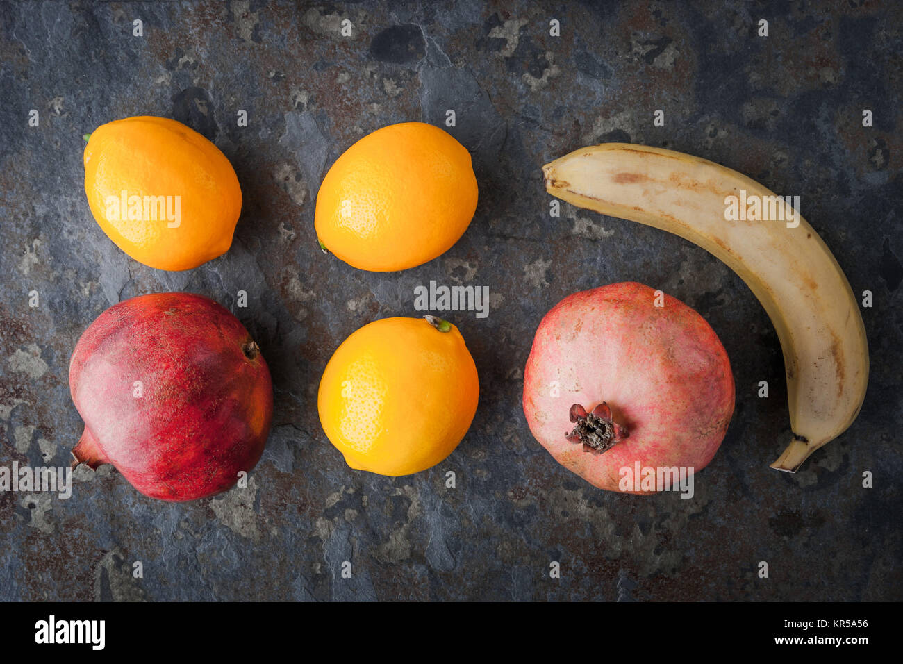 Zitronen, Granatäpfel und Bananen auf den steinernen Tisch Stockfoto