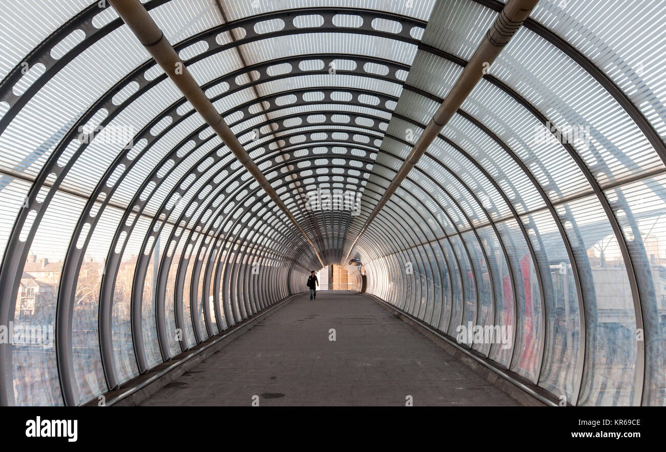 London, England, UK - 10. Dezember 2011: Ein Fußgänger Spaziergänge entlang eine moderne, verglaste Fußgängerbrücke in der Nähe der Docklands East London. Stockfoto