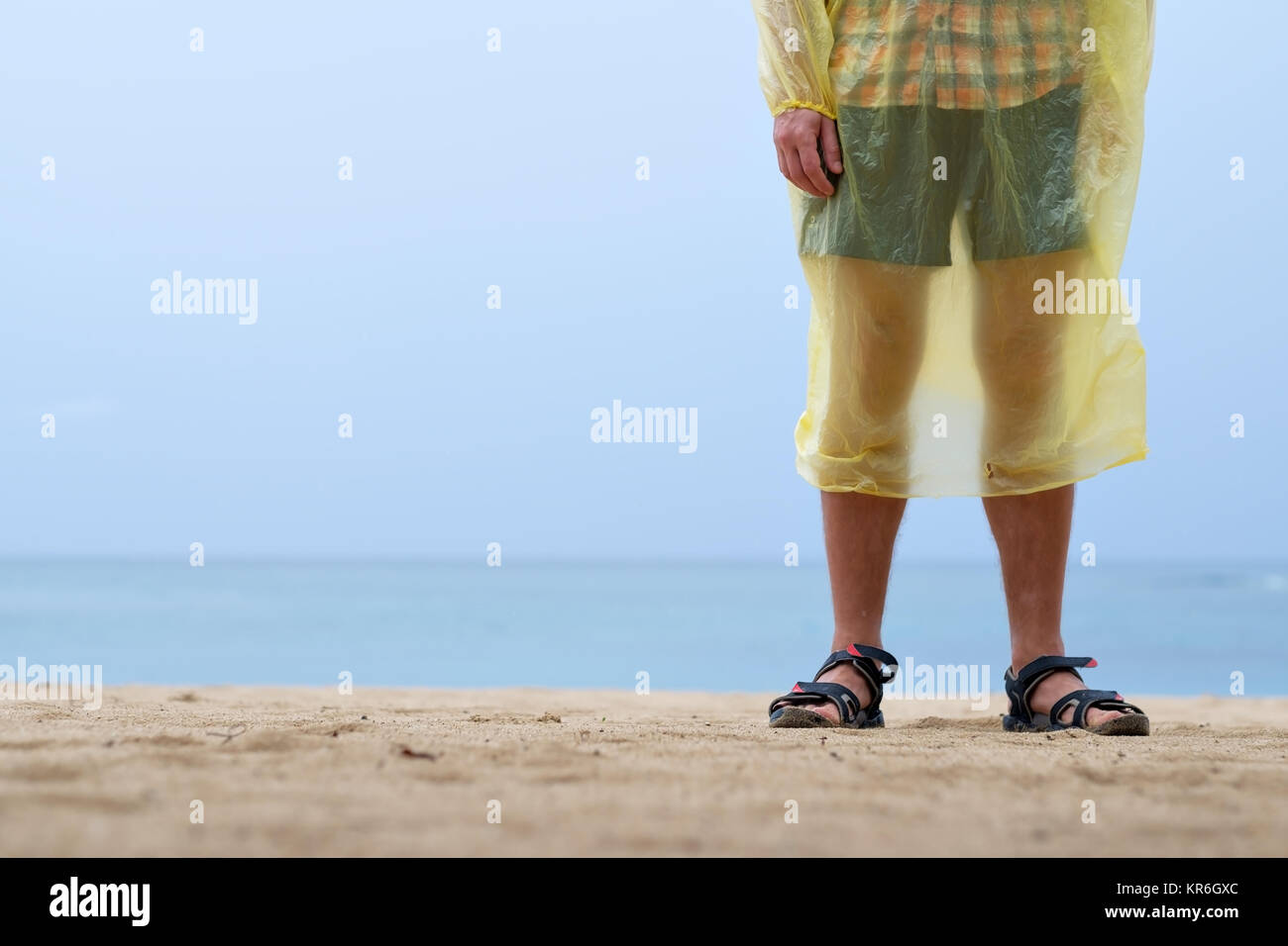 Mann auf den Ozean oder die Küste in Regenjacke. Das schlechte Wetter während der Sommerferien Stockfoto