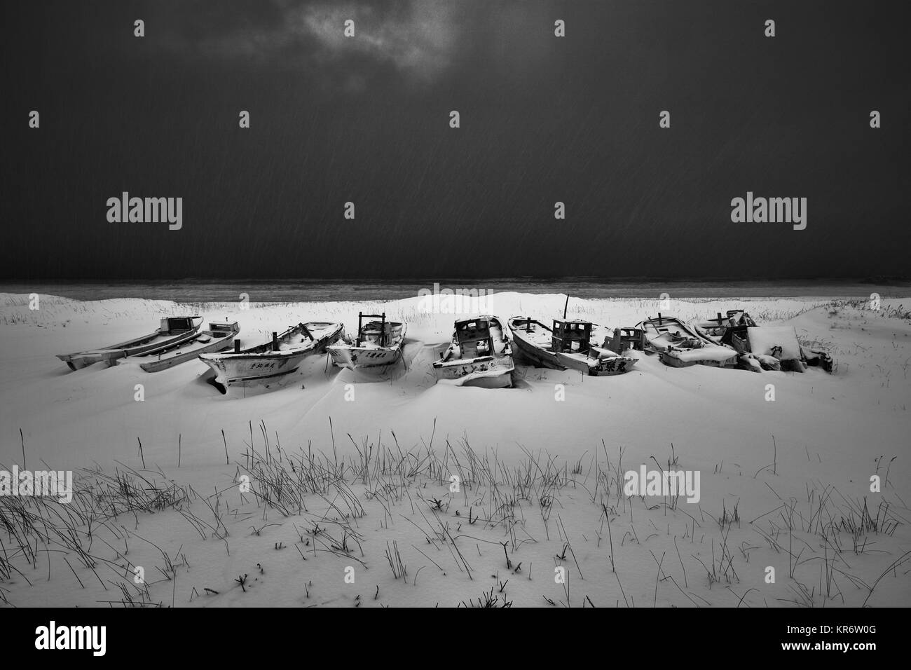 Fischerboote liegen auf trockenem Land in Schnee und Eis im Winter abgedeckt. Stockfoto