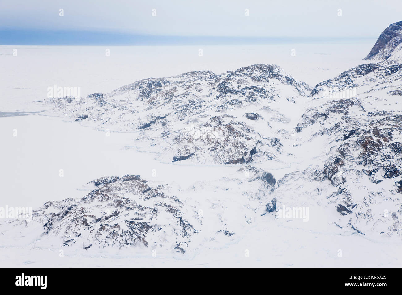 Hohe Betrachtungswinkel von Rocky Winterlandschaft mit Schnee und Eis bedeckt, mit Blick auf das Meer in der Ferne. Stockfoto