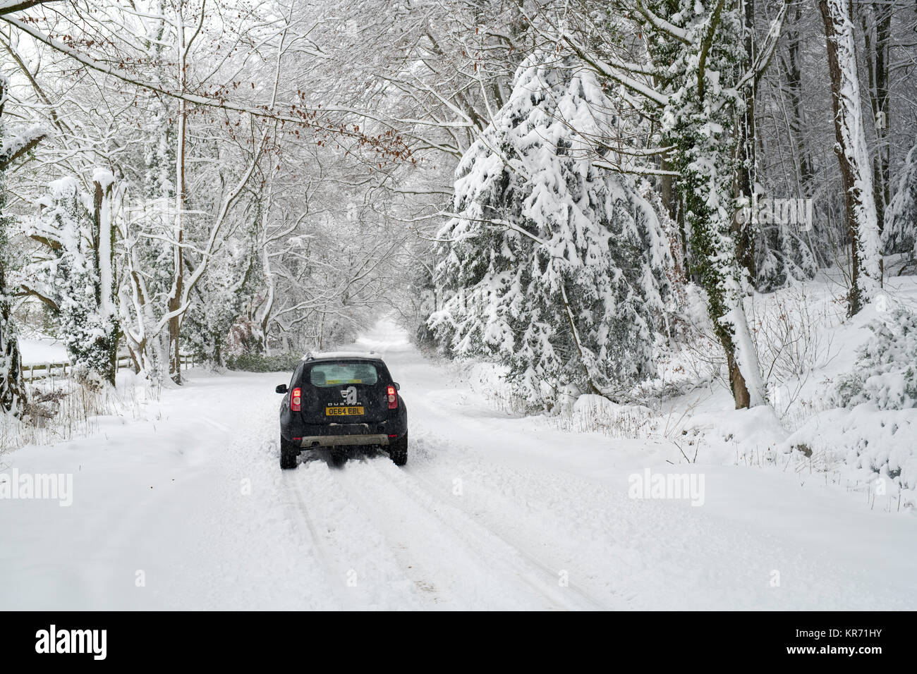 Der Dacia Duster Fahrt auf einer verschneiten Landstraße in der Nähe von Snowshill Dorf im Dezember. Snowshill, Cotswolds, Gloucestershire, England Stockfoto