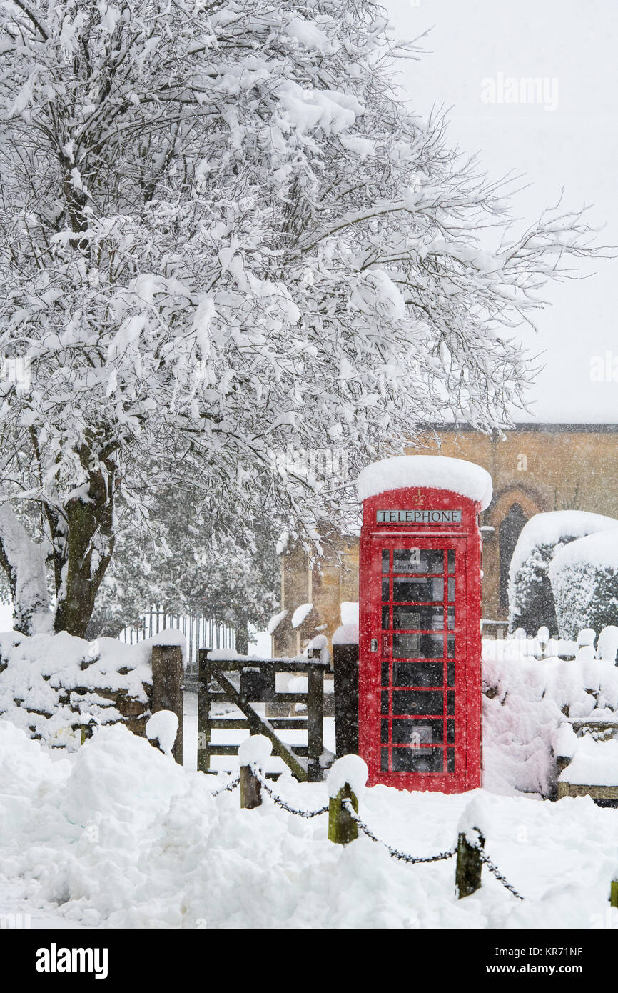 Rote Telefonzelle in Snowshill Dorf im Schnee im Dezember. Snowshill, Cotswolds, Gloucestershire, England. Stockfoto