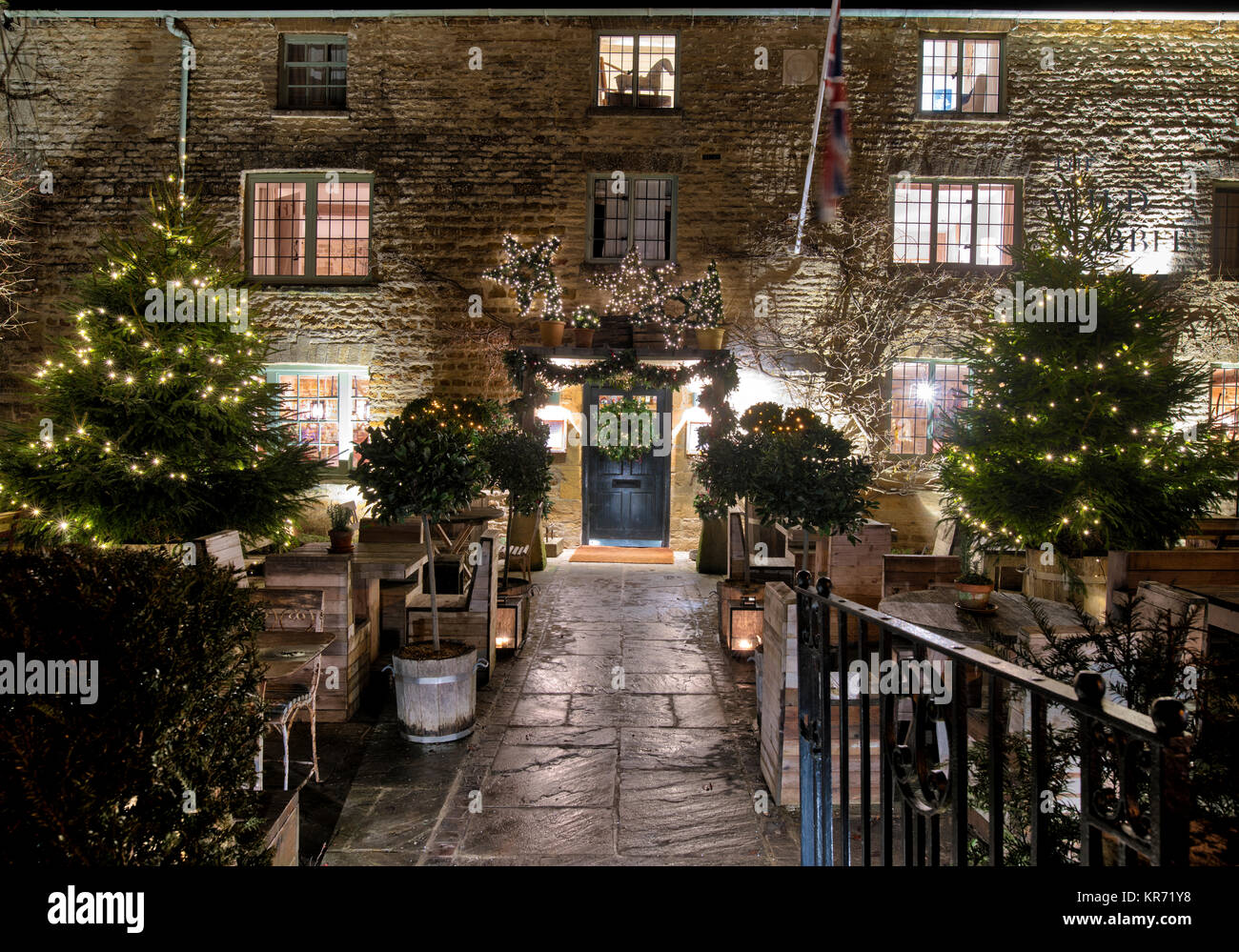 Die wilden Kaninchen Pub mit Weihnachtsbäumen und Dekorationen in der Nacht in Kingham im Dezember. Kingham, Cotswolds, Oxfordshire, England Stockfoto