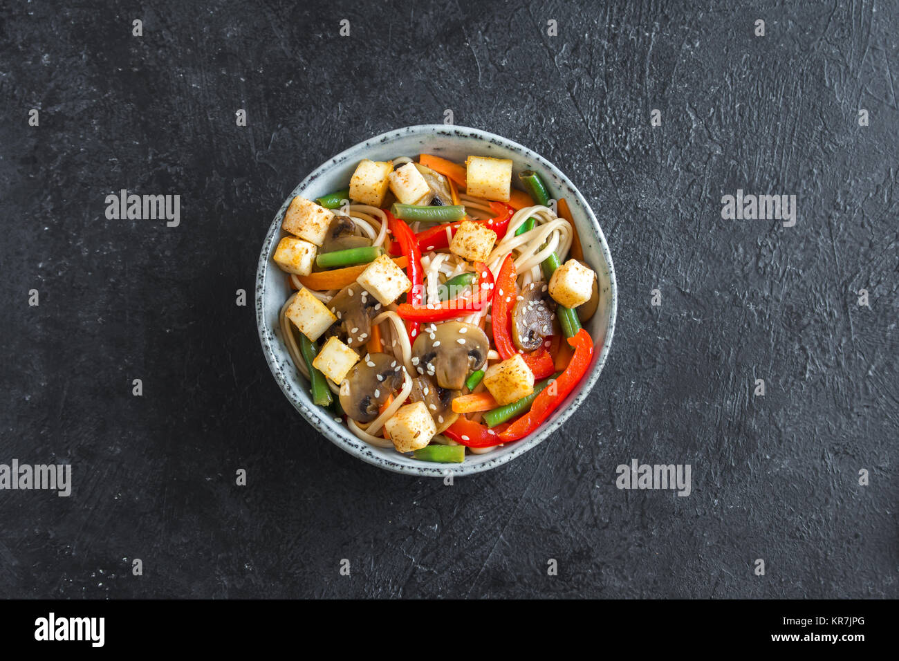 Pfannengerichte mit Udon-nudeln, Tofu, Pilzen und Gemüse. Asiatische vegan vegetarisch essen, Mahlzeit, Bundesrepublik Jugoslawien über schwarzen Hintergrund rühren, kopieren. Stockfoto