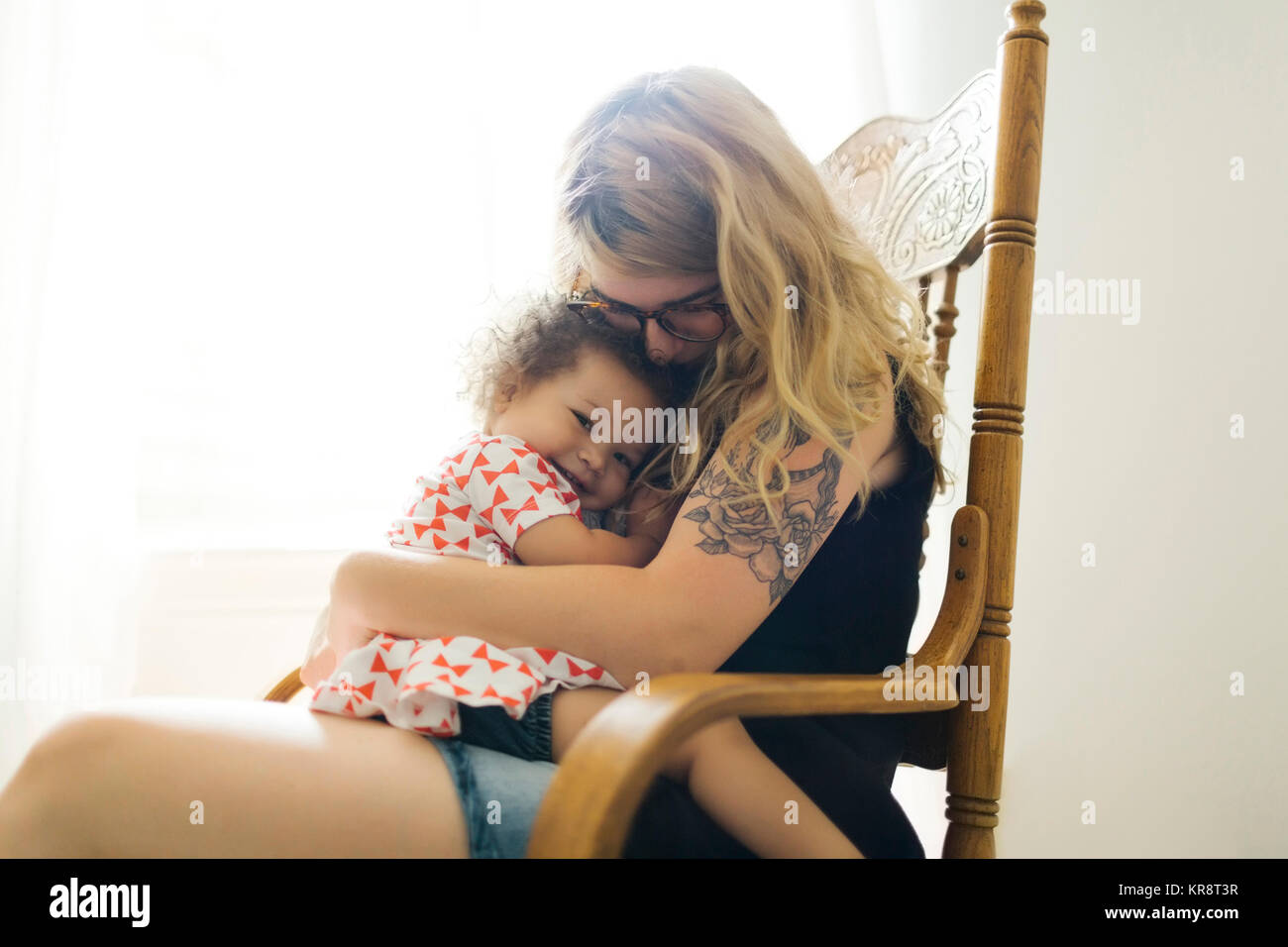 Mutter sitzt auf einem Stuhl und rockigen Tochter (12-17 Monate) Stockfoto