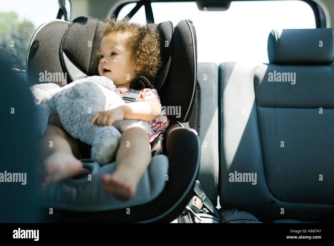 Mädchen (12-17) sitzen auf Auto Sitz und Holding Plüsch Spielzeug Stockfoto