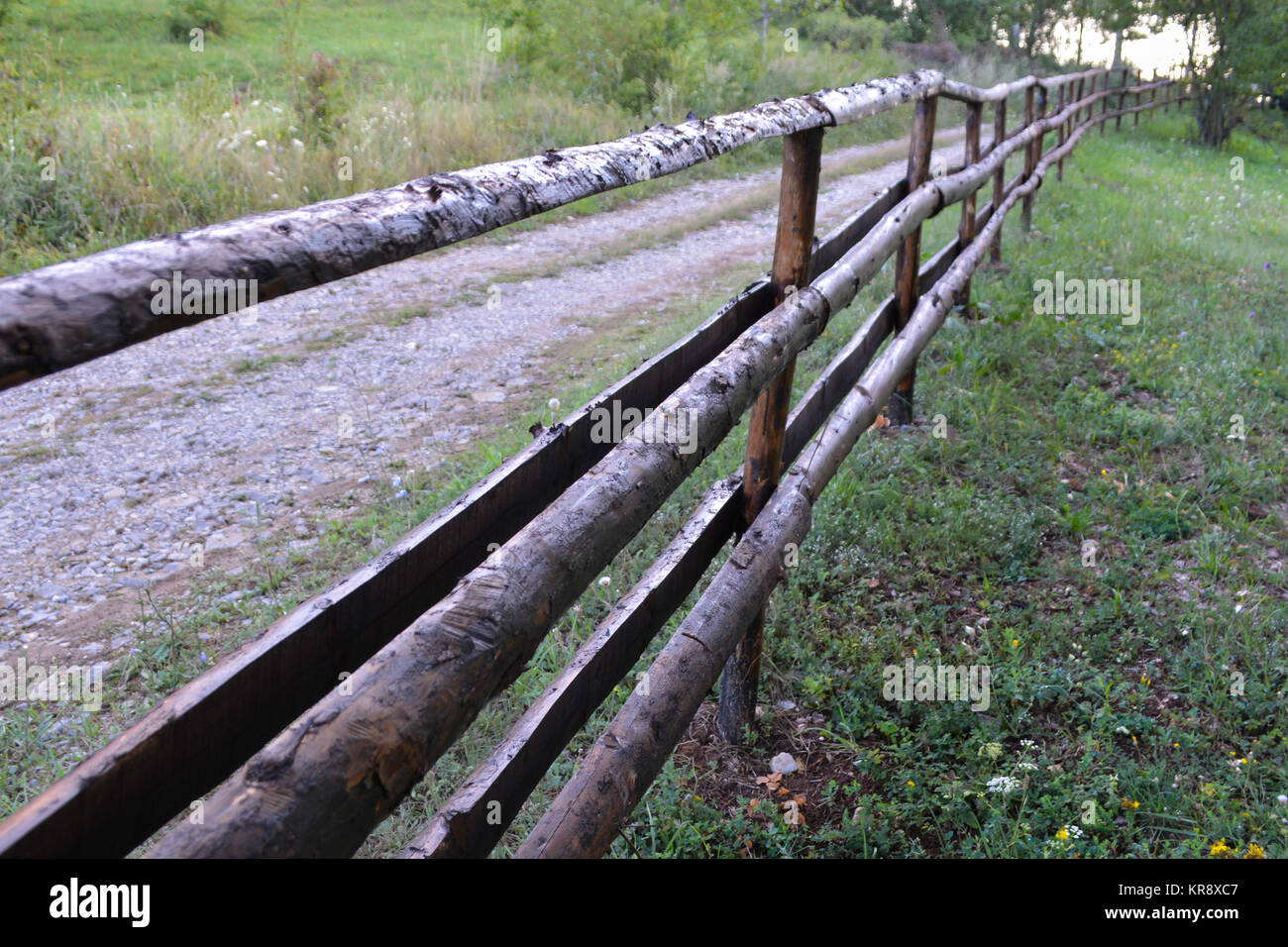 Alte ländliche Holzzaun auf der Straße durch den Wald Stockfoto