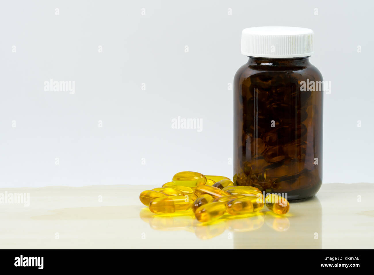 Gelber Fisch öl Kapsel Pillen mit braunen Glasflasche mit leeren Etikett auf dem Tisch mit Platz für Text kopieren. Vitamine und Nahrungsergänzungsmittel für Herz Pflege Stockfoto