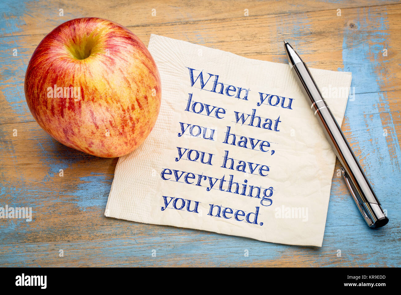Wenn Sie lieben, was Sie haben, haben Sie alles was man braucht - inspiraitonal Handschrift auf eine Serviette mit einem frischen Apfel Stockfoto