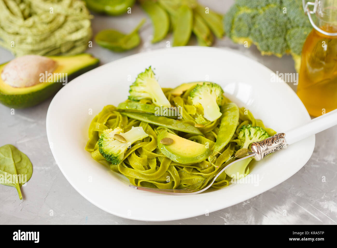 Gesunder Spinat Nudeln mit Brokkoli, Avocado, Kürbiskerne und grünen Erbsen. Vegane Ernährung Essen Konzept. Stockfoto