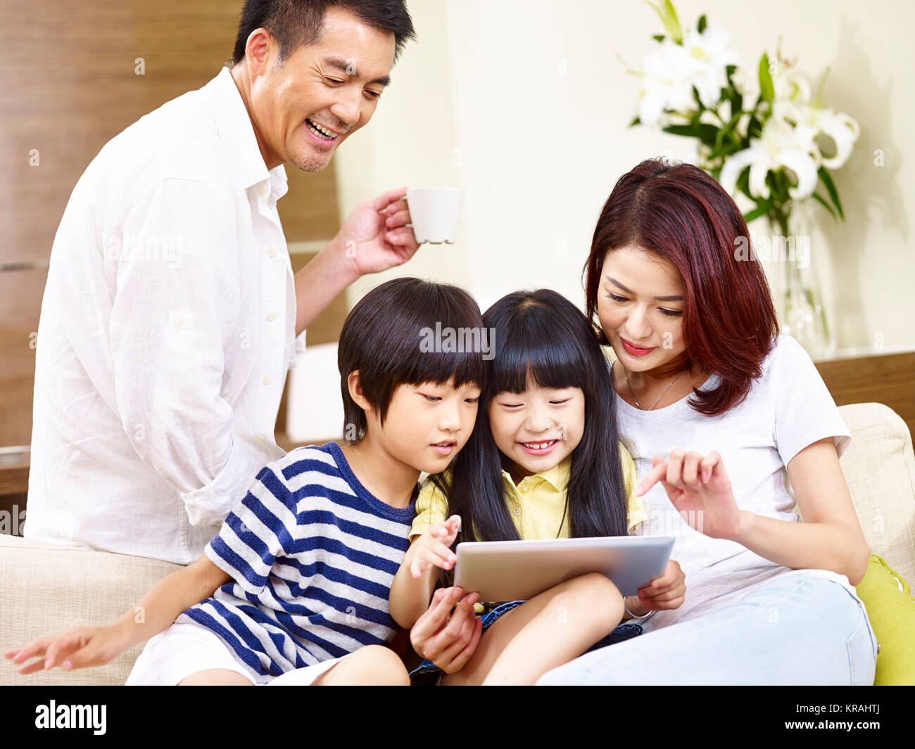 Asiatische Eltern Vater und Mutter und zwei Kinder Sohn und Tochter sitzen auf Familie Couch mit digitalen Tablet zusammen. Stockfoto