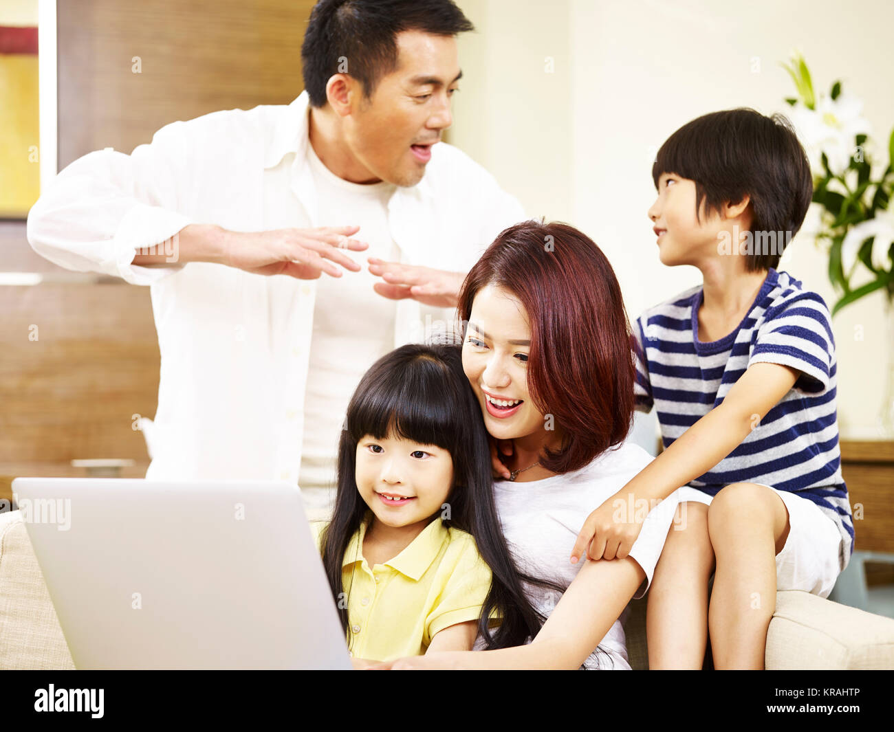 Asiatische Eltern Vater und Mutter und zwei Kinder Sohn und Tochter sitzen auf Familie Couch mit Laptop Computer zusammen. Stockfoto