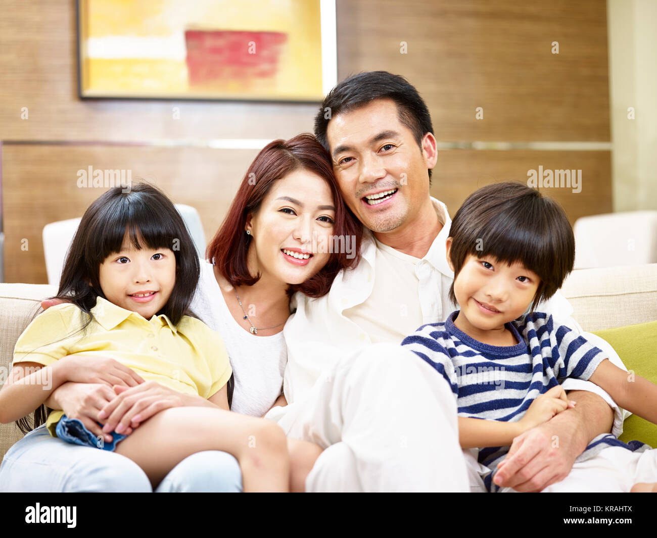 Portrait eines glücklichen asiatischen Familie zu Hause auf der Couch sitzen mit Blick auf die Kamera zu lächeln. Stockfoto