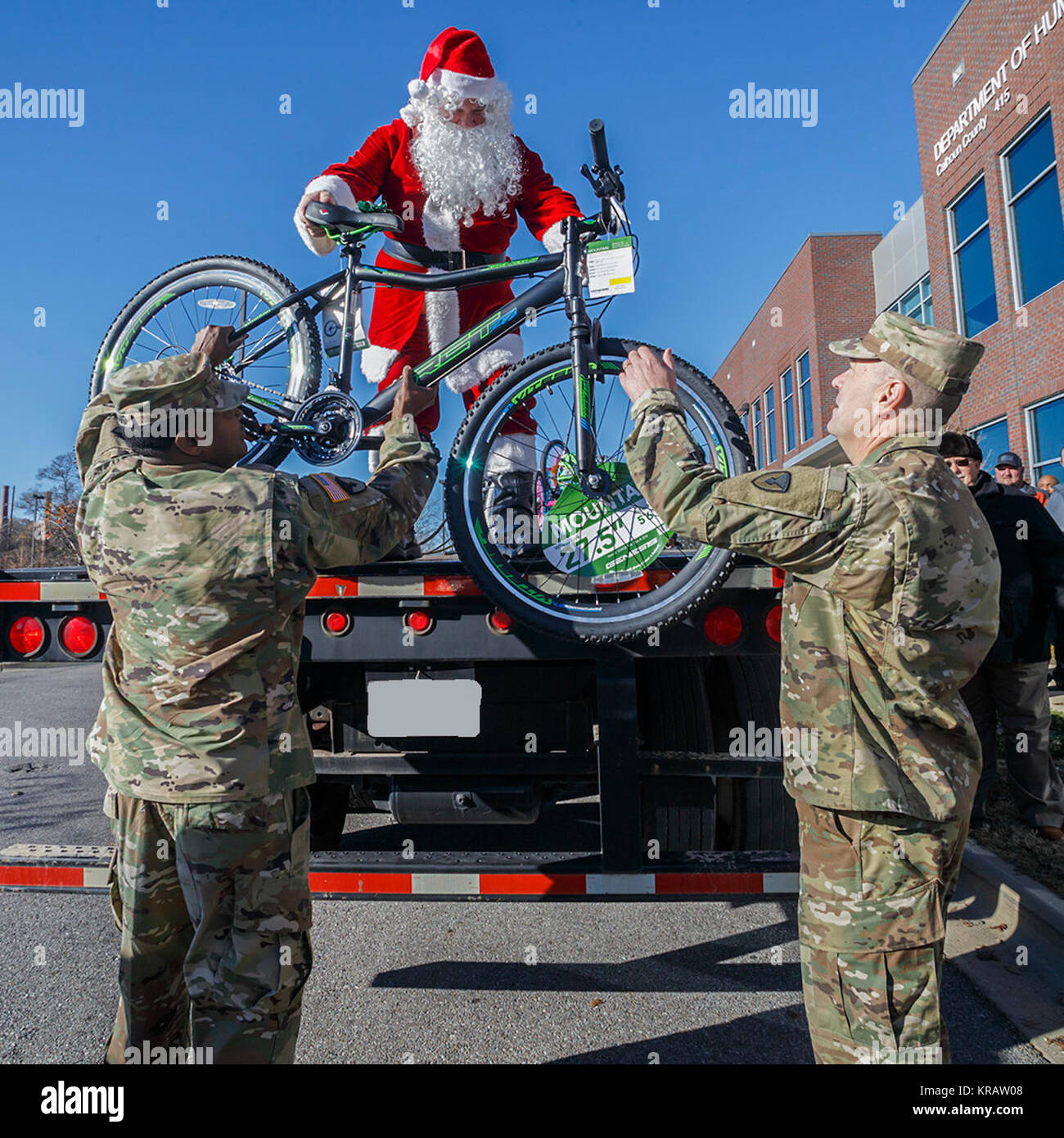 Santa Hände, ein Fahrrad zu Anniston Army Depot Sgt. Maj. Ronald Ferdinand und Tank, Automotive und Rüstung Befehl Kaplan Oberstleutnant David Snyder am Calhoun County Abteilung der menschlichen Ressourcen. Der Depot 2017 Weihnachtsatmosphäre Programm Dez. 13 gipfelte mit der Lieferung von drei LKW-Ladungen von Geschenken und Fahrräder in die DHR-Büro in Anniston. Stockfoto