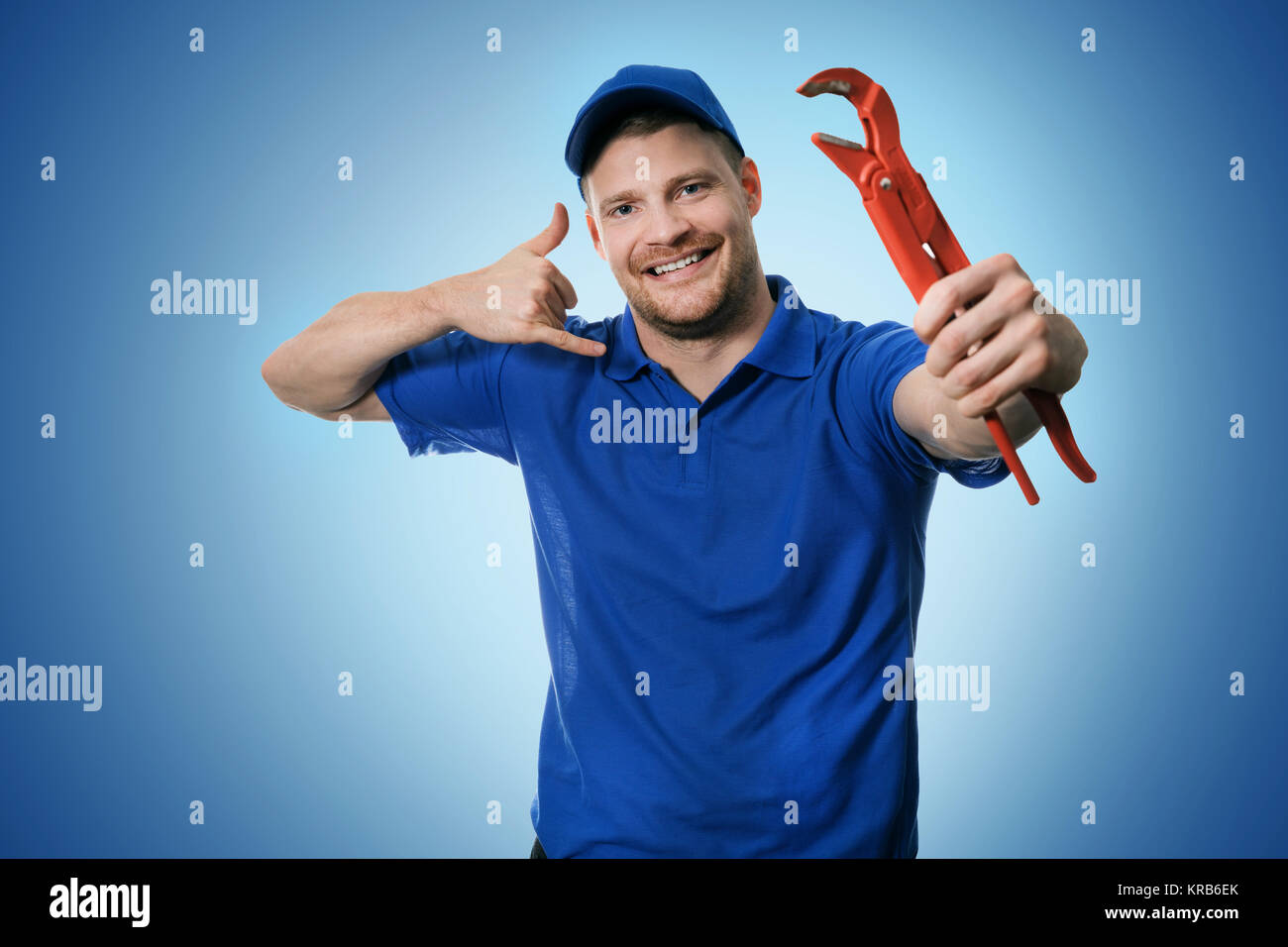 Sanitär - klempner mit Schlüssel angezeigt Anruf Geste auf blauem Hintergrund Stockfoto