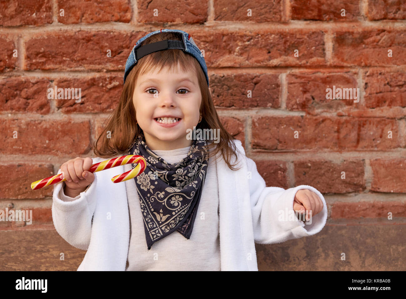 Schöne niedliche Kind Süßigkeiten essen. Portrait von niedlichen kleinen Mädchen im Baseball Cap Stockfoto