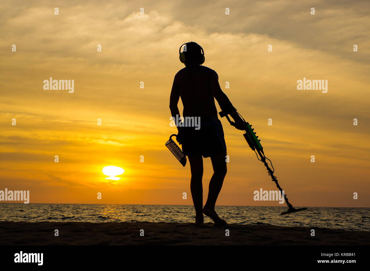 Treasure Hunter mit Metalldetektor auf den Sonnenuntergang am Strand Stockfoto