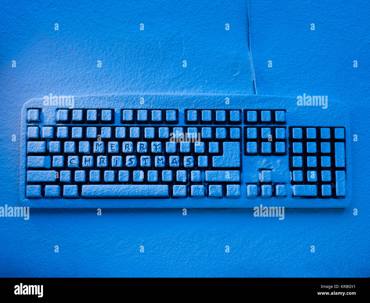 Computer Tastatur mit Schnee bedeckt durch blaues Neonlicht beleuchtet mit Aufschrift frohe Weihnachten Stockfoto