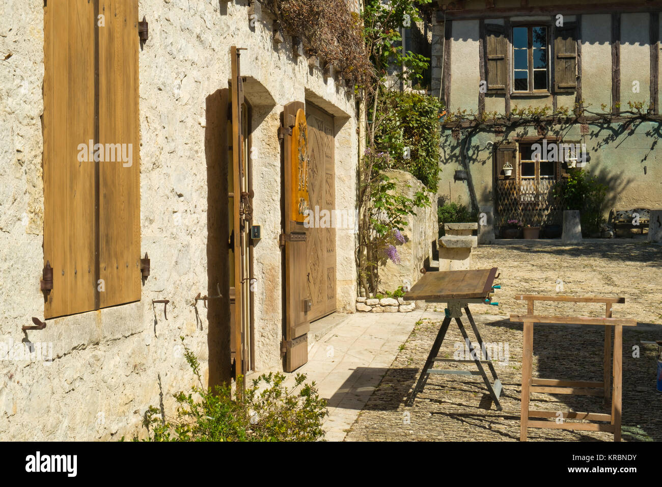 Traditionelle hölzerne Fensterläden, repariert und neu lackiert warten auf eine Werkbank außerhalb einer idyllischen alten Cottage in Pujols, Lot-et-Garonne, Frankreich Stockfoto