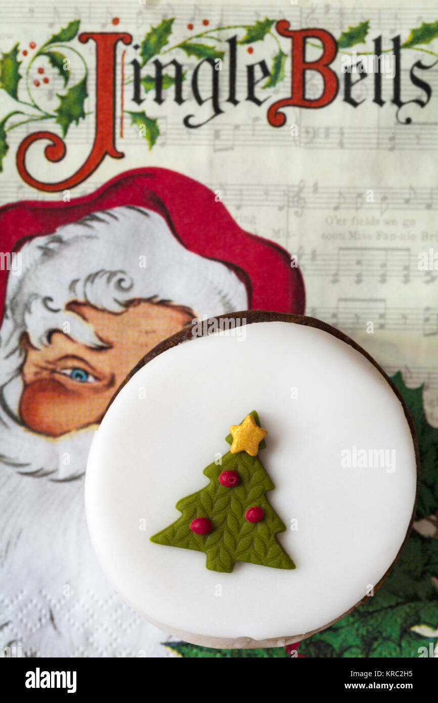 Tesco Mini top iced Christmas Cake - reiche Frucht Kuchen mit glace Kirschen, gekrönt mit Marzipan und dekorativen Vereisung auf Jingle Bells serviette Stockfoto