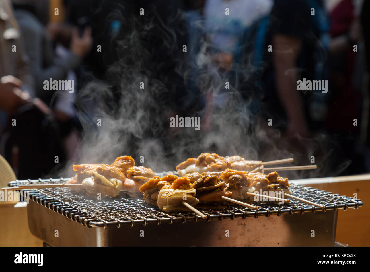 Jakobsmuscheln und Meer ​​urchin Eier Spieß Grill mit Rauch, japanisch Essen in Tsukiji Fischmarkt, Japan. selektive Fokus Stockfoto