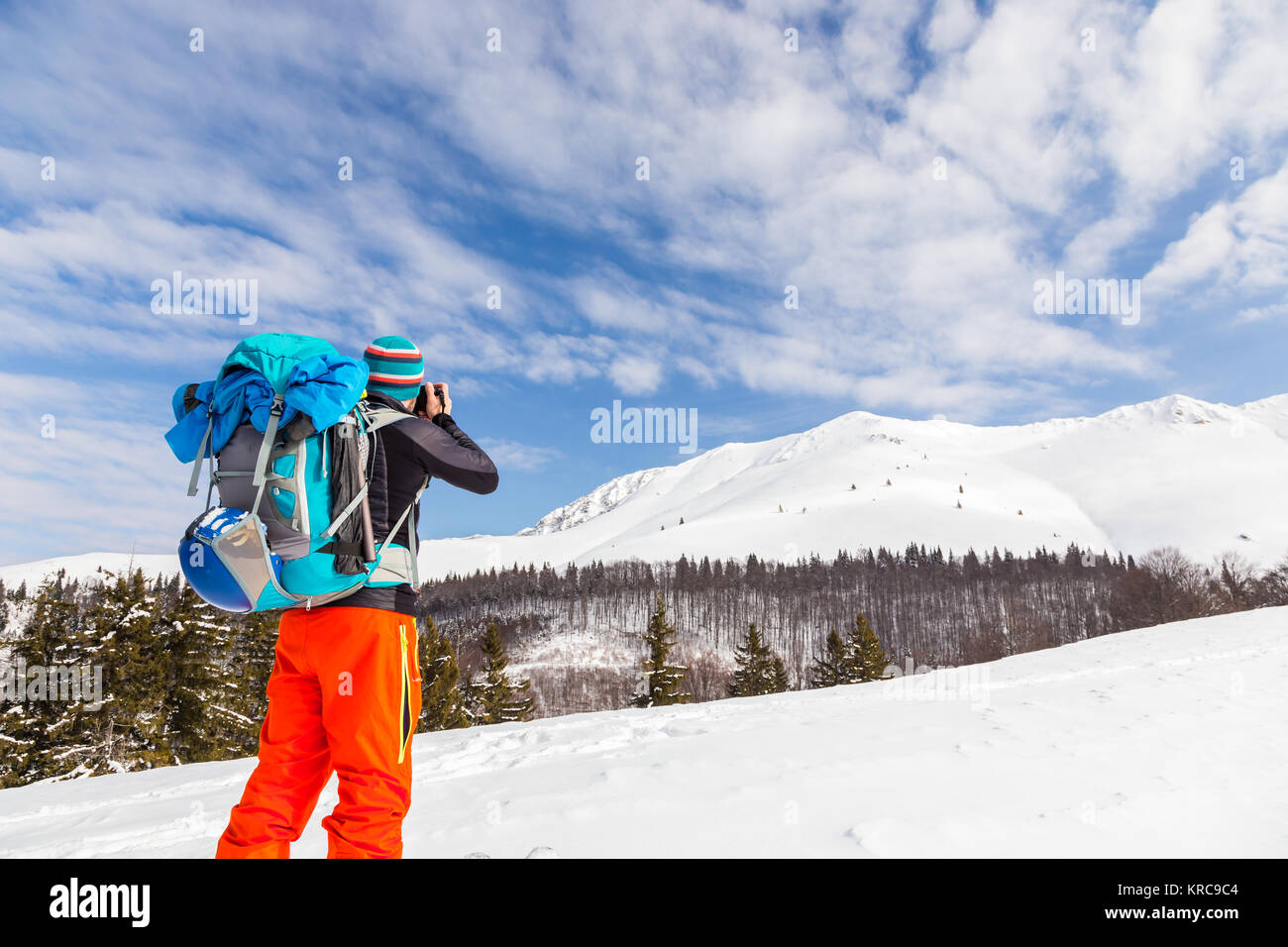 Jungen kaukasischen Mann Fotograf Bilder sprechen während backcountry Skiing an einem schönen sonnigen Tag mit frischem Schnee Stockfoto