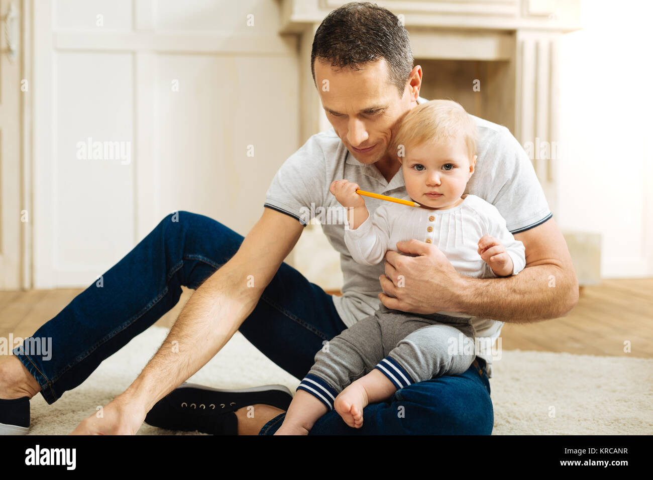 Nettes ruhiges Kind mit einem Bleistift und Suchen froh, während er mit Vater Stockfoto