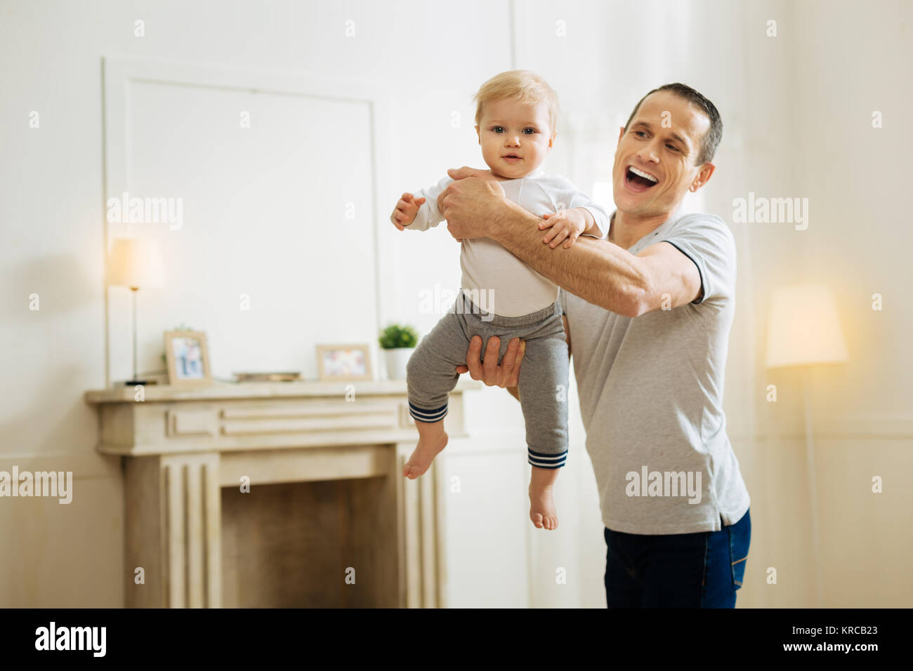 Positive Vater Lachen beim Spielen mit seinen süßen Ruhe Kind aufgeregt Stockfoto