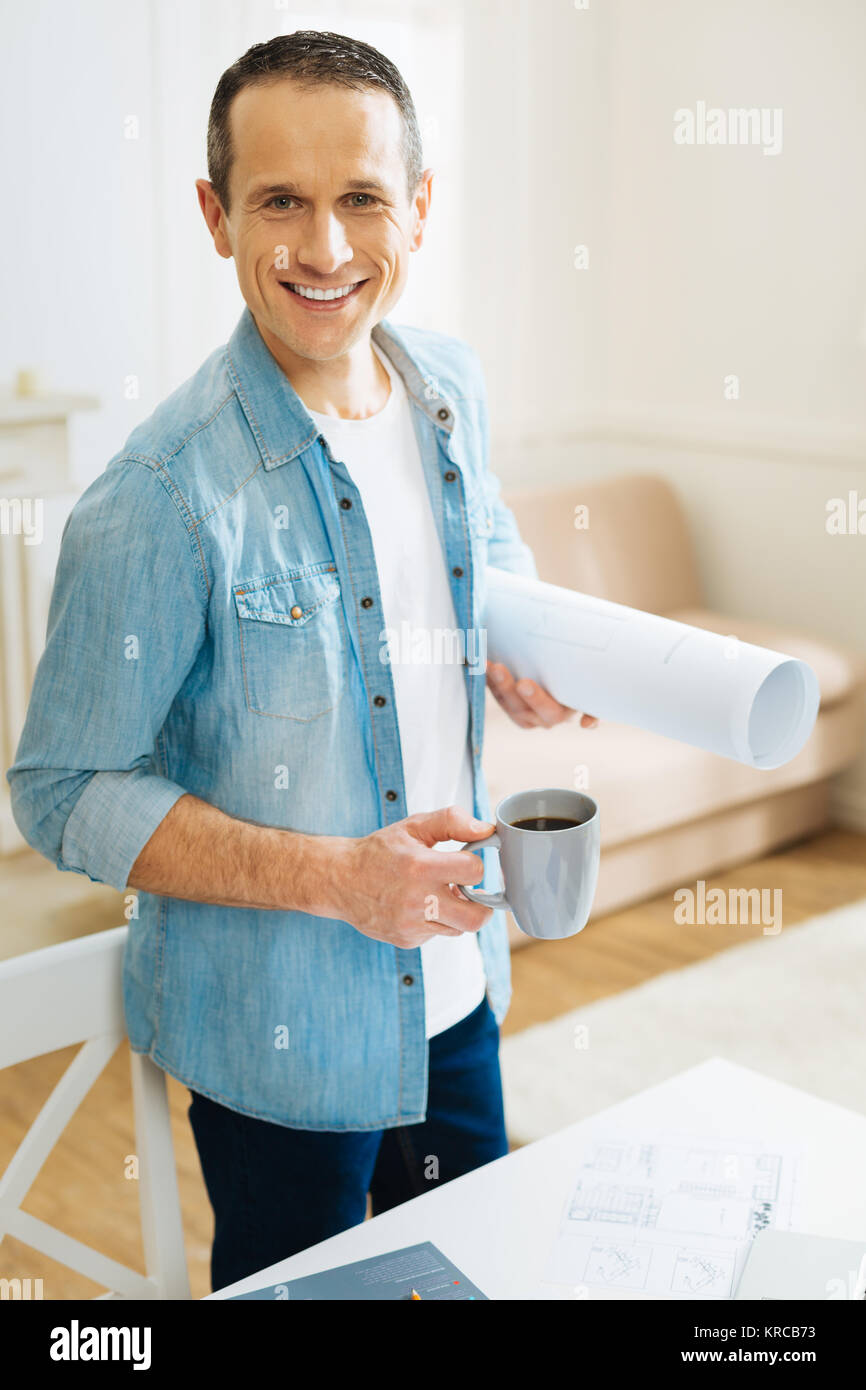 Angenehme schöne Ingenieur Gefühl begeistert beim Stehen mit einer Tasse Tee Stockfoto