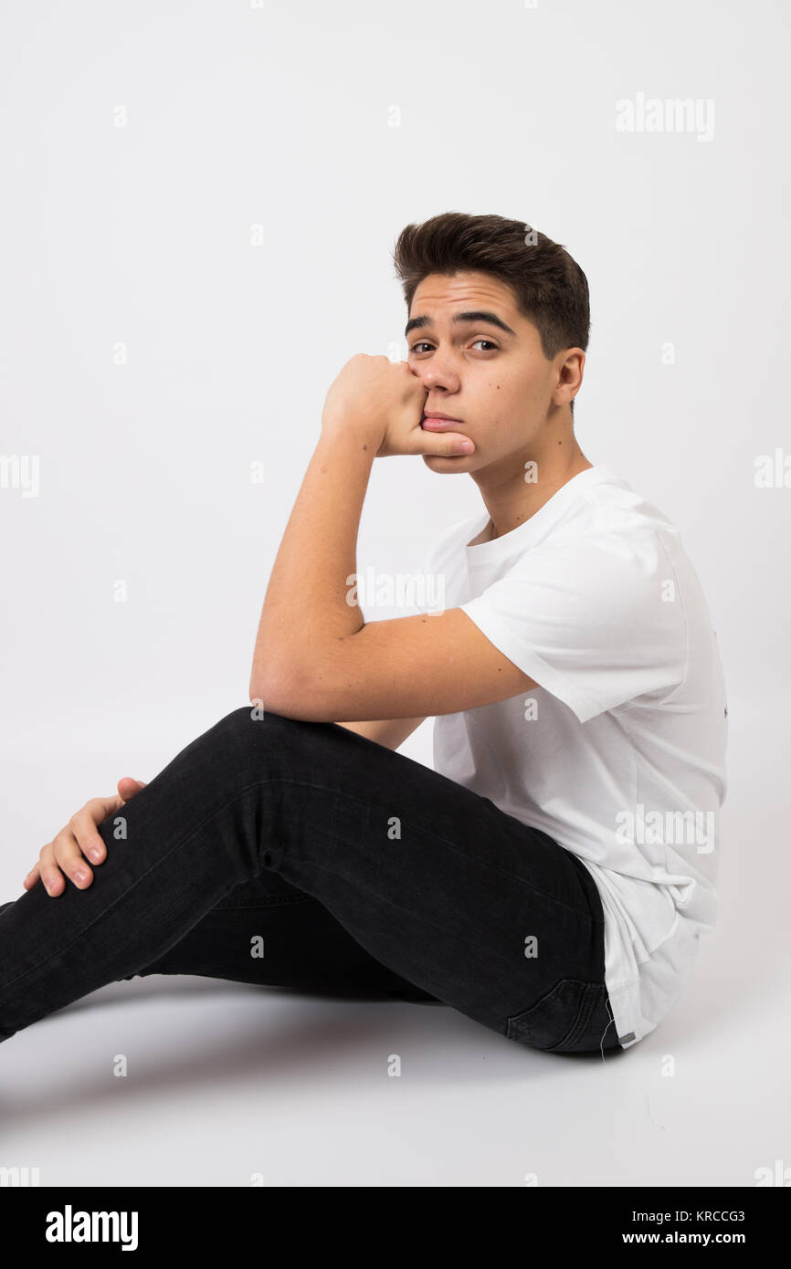 Teenager gewagte im Fotostudio mit weißem T-Shirt und Jeans mit weißem Hintergrund Stockfoto