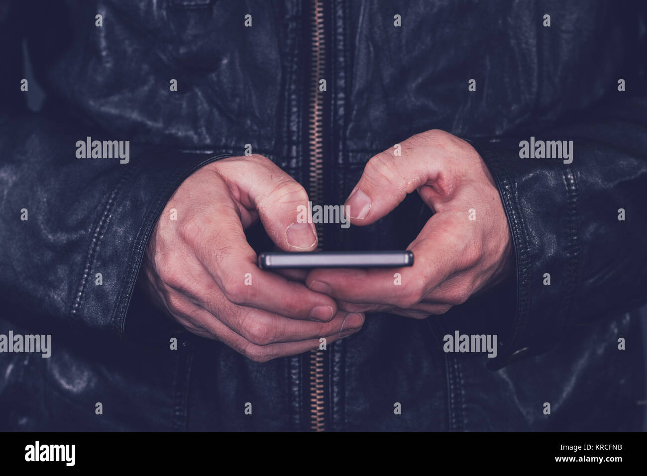 Mann in der Lederjacke mit Handy für den Versand von SMS. Moderne Technologie und lifestyle Konzept. Stockfoto