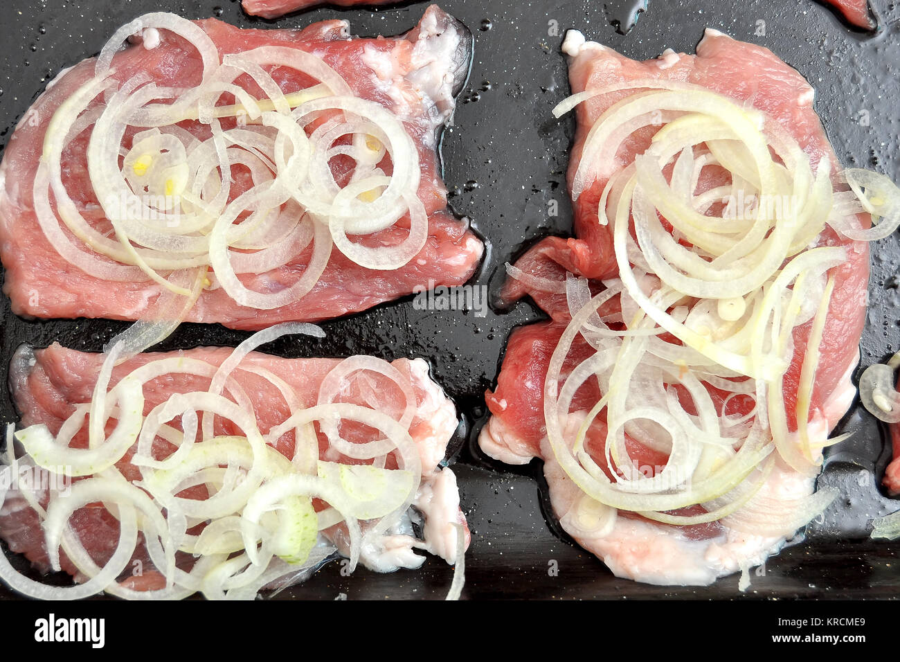 Raw Schweinekoteletts auf einem schwarzen Backblech Prozess des Kochens Schritt für Schritt. Ansicht von oben, flach. Stockfoto