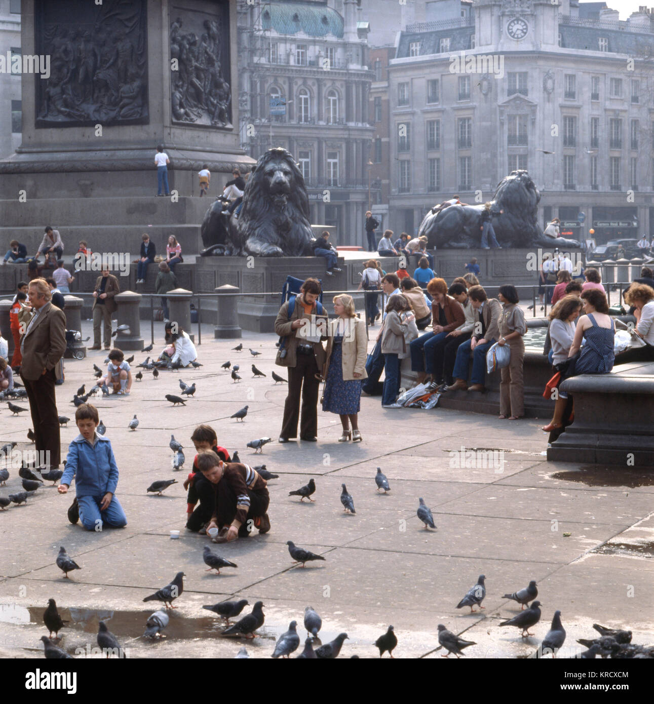 Typische Touristen füttern Tauben um Edwin Landseer's Löwen an der Basis der Nelson's Column auf den Trafalgar Square, Central London. Datum: 1980 Stockfoto