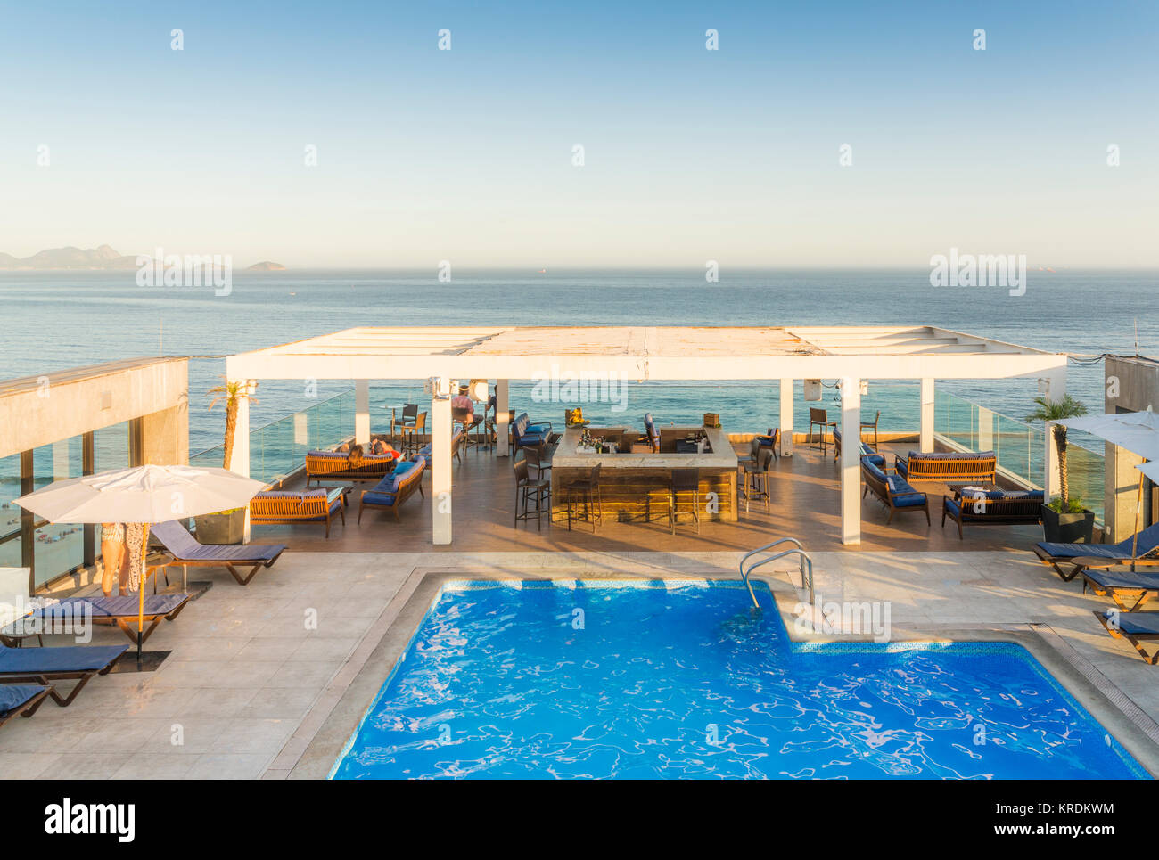 Luxuriöse Pool und eine Lounge mit Bar, mit Blick auf den tropischen Ozean während der Goldenen Stunde - in Rio de Janeiro, Brasilien erfasst Stockfoto