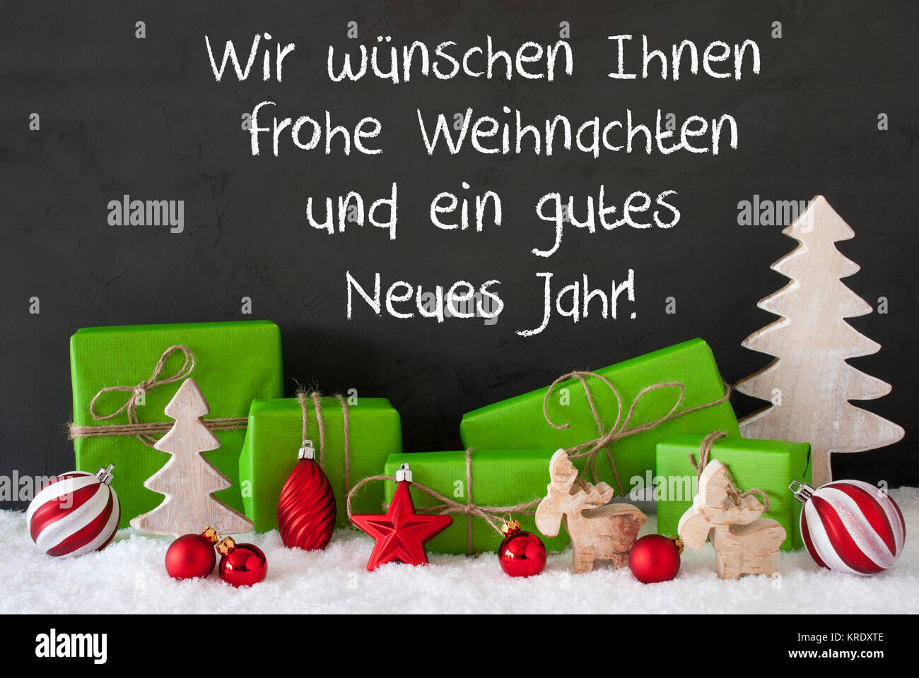 Deutsche Text Wir wuenschen Ihnen Frohe Weihnachten und ein Gutes neues  Jahr, frohe Weihnachten und ein glückliches Neues Jahr. Geschenke  Dekoration wie Baum, Elche oder roten Ball. Schwarz Zement Hintergrund mit  Schnee