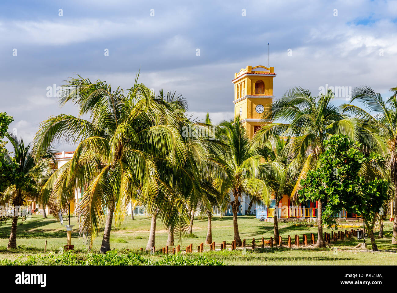 Gelb Clock Tower mit Palmen an der Front, nahe Strand Ancon, Trinidad, Kuba Stockfoto