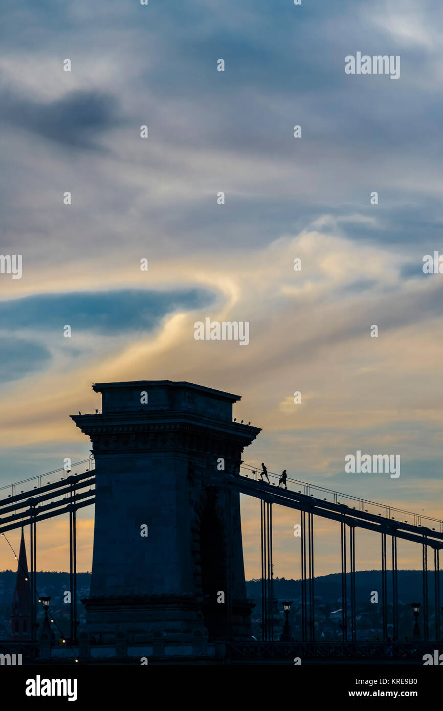 Silhouette von Chain Bridge bei Sonnenuntergang, Budapest, Ungarn. Silhouette von Menschen klettern eine Brücke, dramatische Himmel. Stockfoto