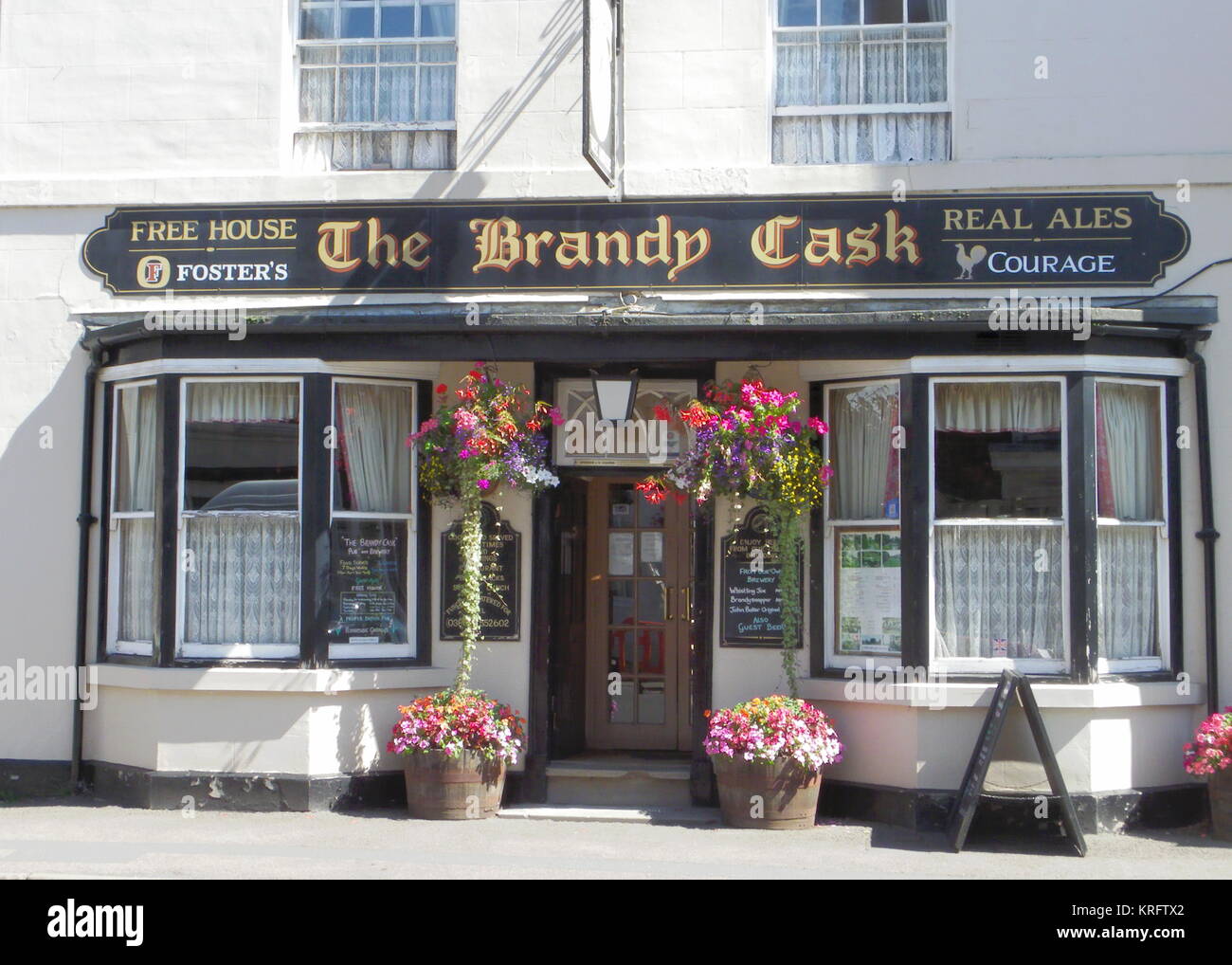 Der Brandy Cask in der High Street, Pershore, Worcestershire, mit farbenfrohen Hängekörben und Blumen in Wannen. Stockfoto